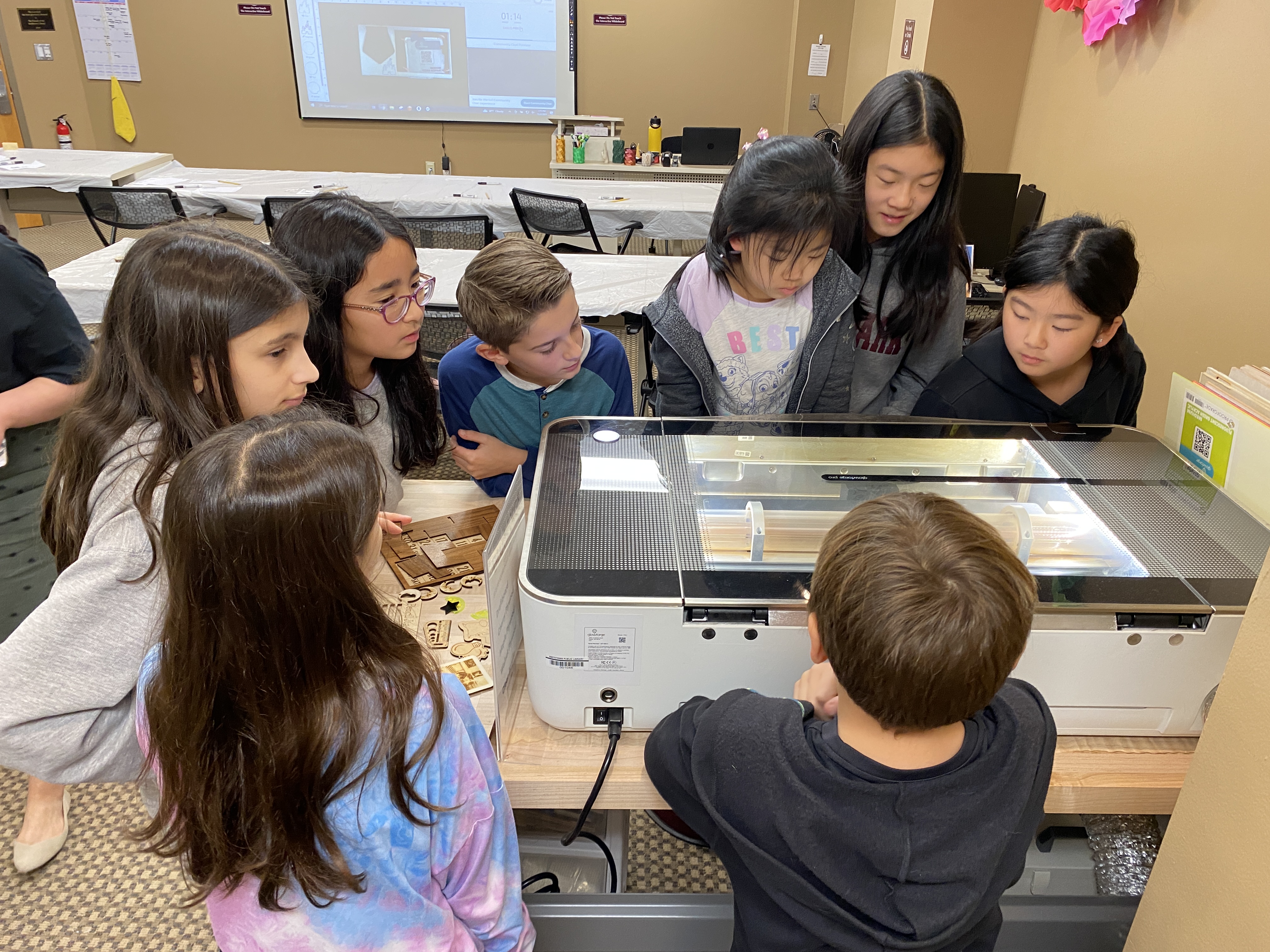 young children watching the laser engraver