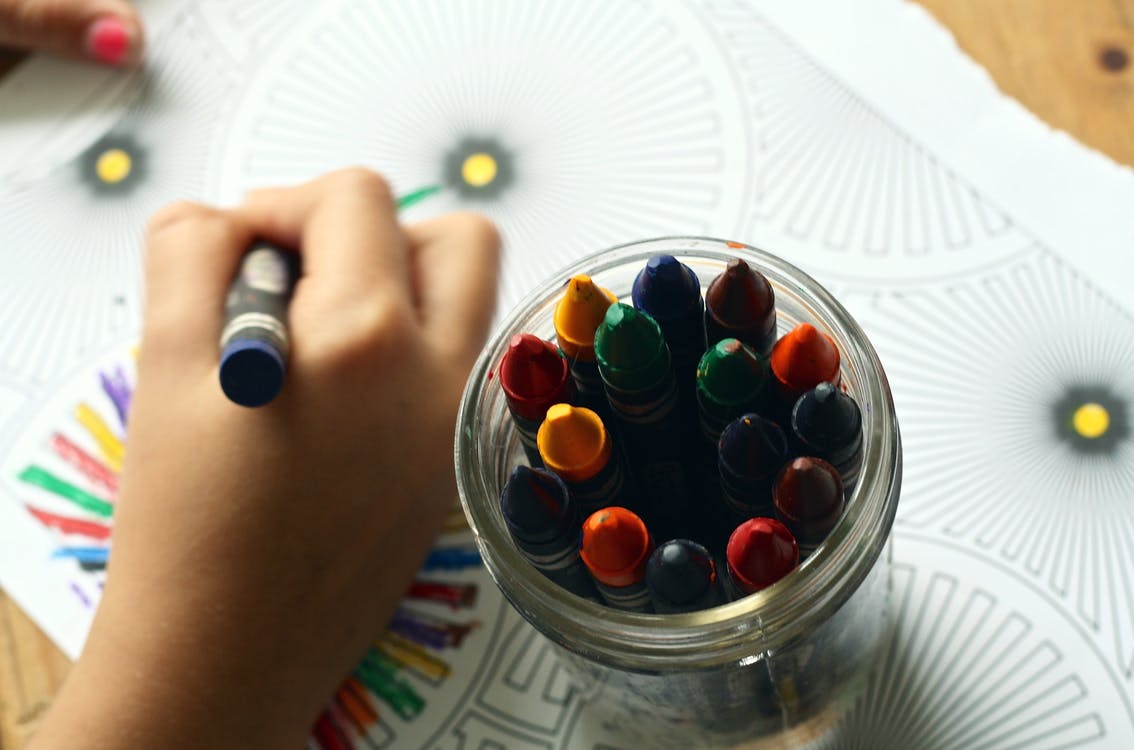Closeup of child coloring on paper with crayons