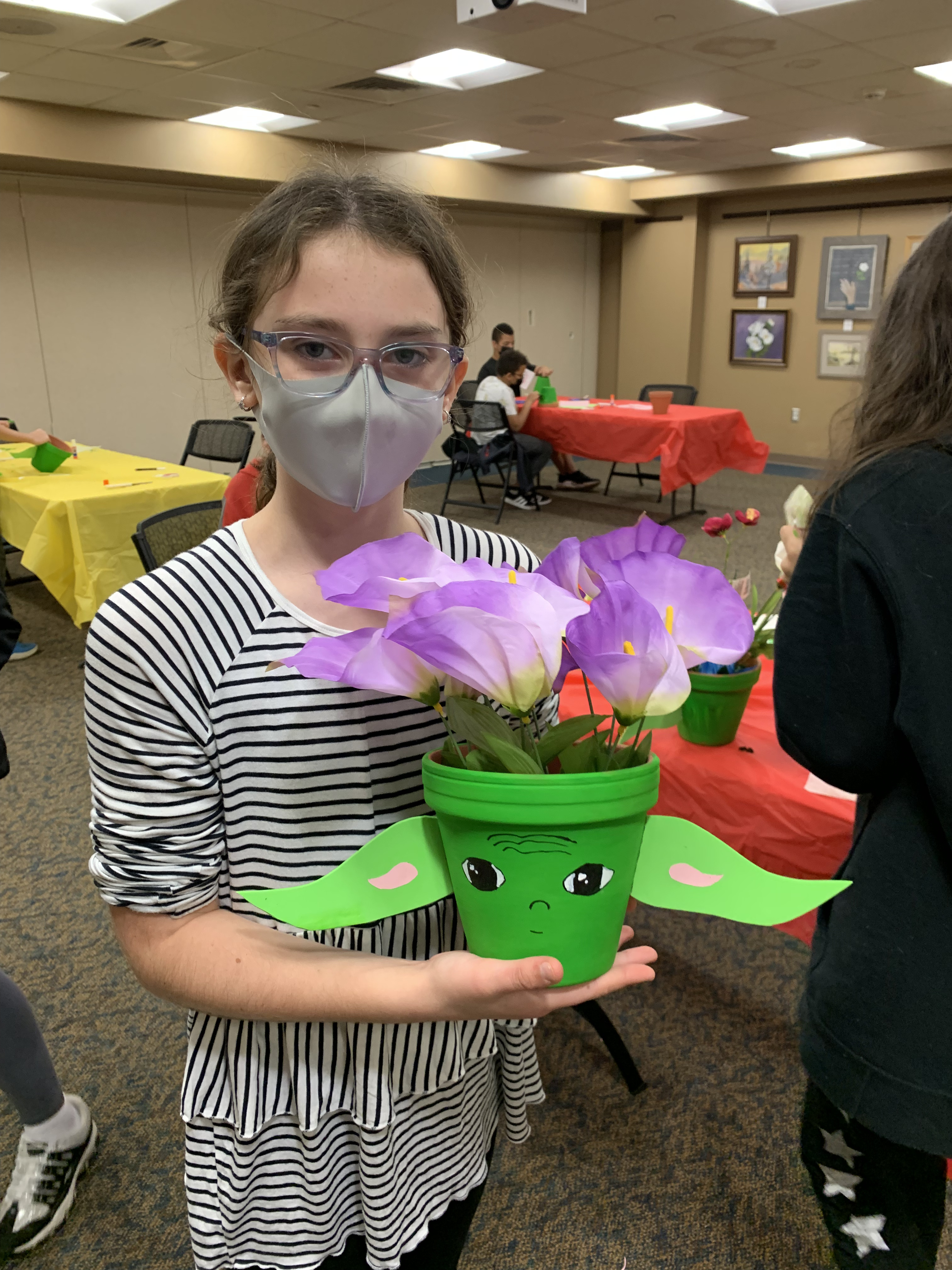 SmithCon image showing a young girl holding her baby Yoda planter that she created