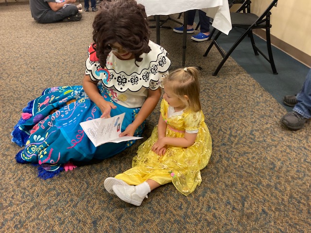 Older Cosplayer woman reading a story to a young girl