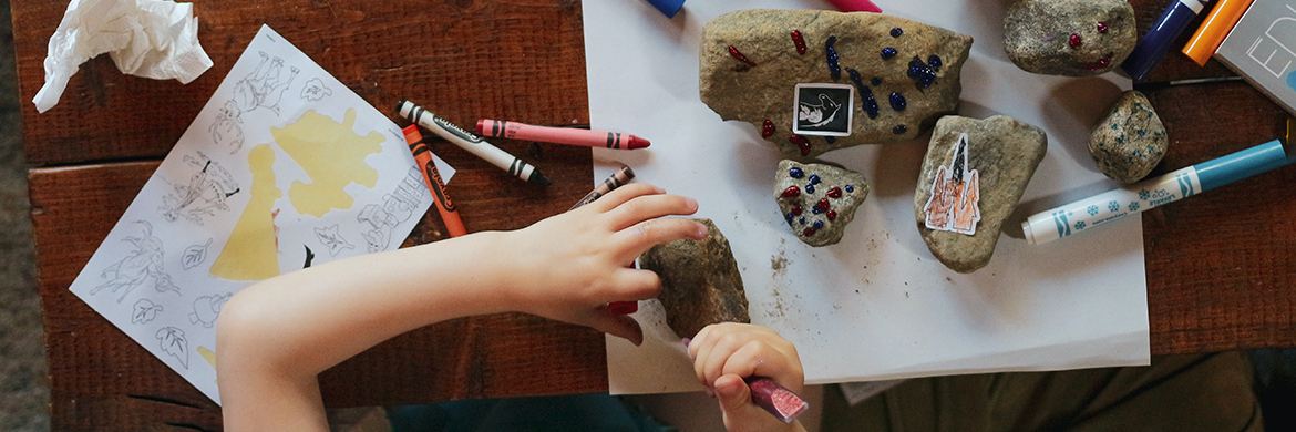 Child making rock creations with various supplies