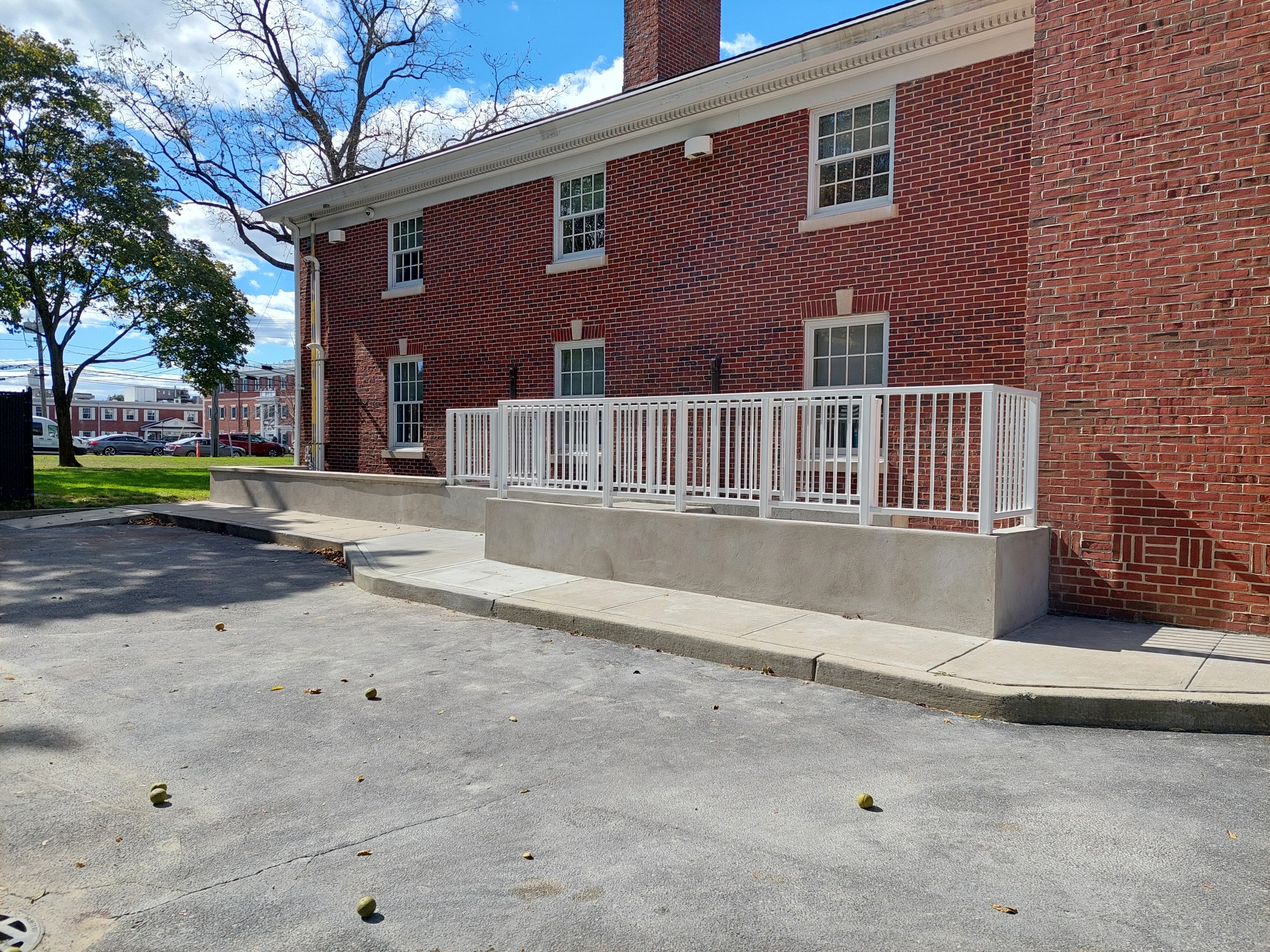 Completed higher grey concrete retaining wall with white metal fencing on top