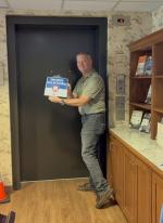 gentleman with dark pants and green shirt removing a sign from the elevator
