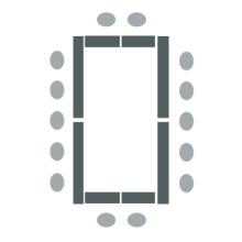 Room set up with multiple tables arranged in a large rectangle with chairs around outside edges