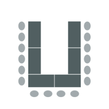 Tables arranged in horseshoe shape with open end facing front of room and chairs around outside edges
